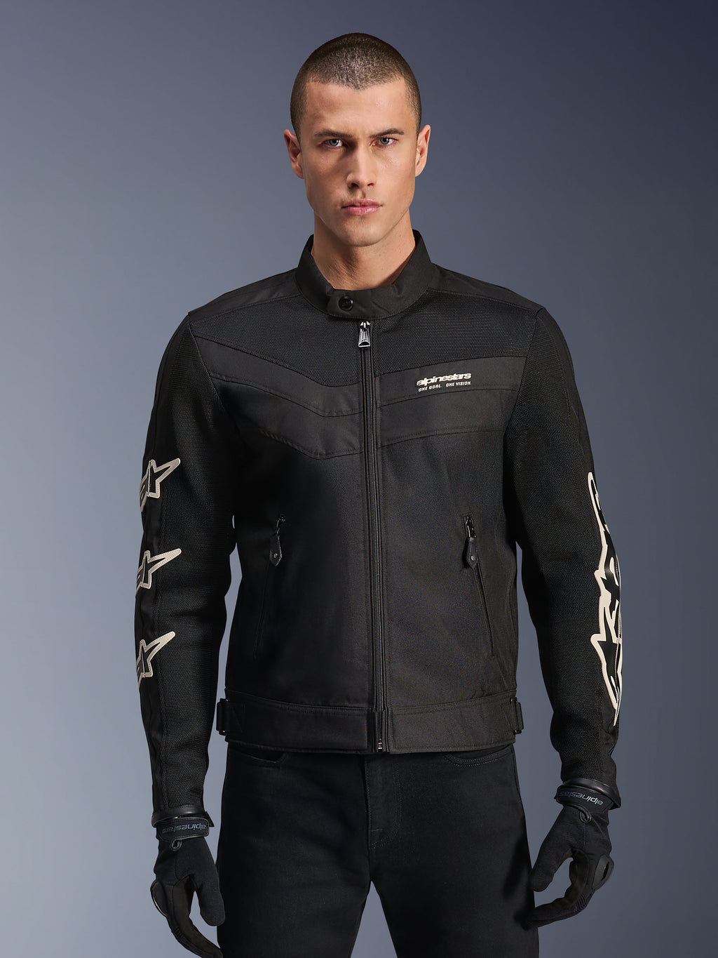 Alpinestars T-Dyno Air jakke, sort motorcykeljakke i tekstil, med hvid stjernegrafik på ærmerne og logo på brystet, mesh-paneler til ventilation, vintage-inspireret bikerpasform, båret med sorte handsker og bukser