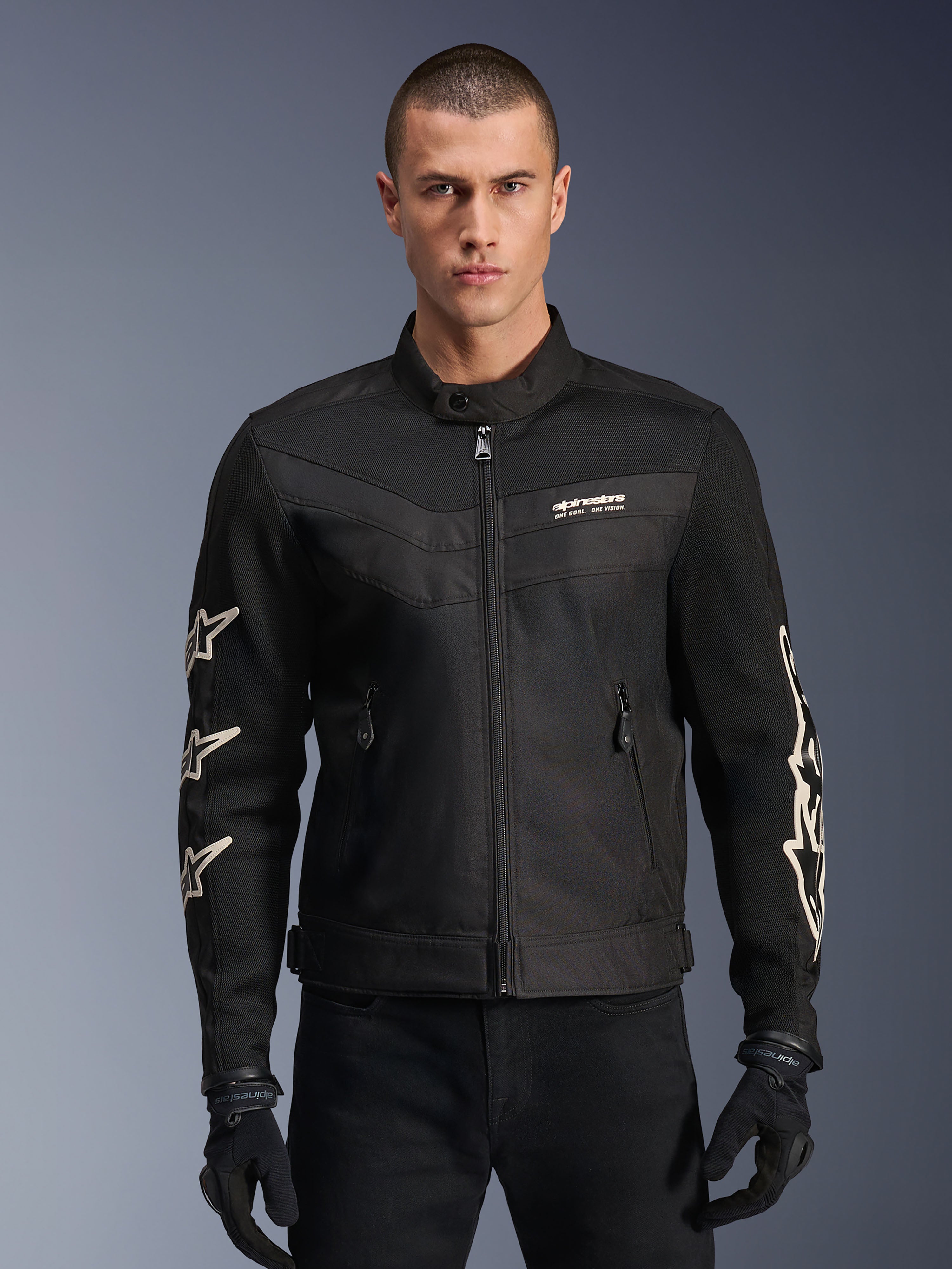 Alpinestars T-Dyno Air jakke, sort motorcykeljakke i tekstil, med hvid stjernegrafik på ærmerne og logo på brystet, mesh-paneler til ventilation, vintage-inspireret bikerpasform, båret med sorte handsker og bukser