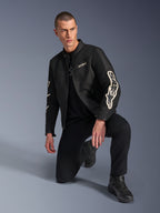 Mandlig model iført Alpinestars T-Dyno Air jakke, sort tekstil-motorcykeljakke med stor hvid branding på ærmerne, kombineret med sorte bukser og kørestøvler, moderne vintage-inspireret design med 3D-mesh-paneler.