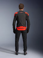 Alpinestars T-Stunt Air Jacket, sort med Red Fluo og mørkerøde detaljer, set bagfra på model, kombineret med sorte kørebukser og støvler, markant Alpinestars-branding på det nederste rygpanel, modulært design med mesh-konstruktion for ventilation.
