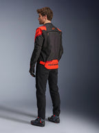 Mand iført Alpinestars T-Stunt Air-jakke set bagfra, sort, rød fluo og mørkerød, tekstil motorcykeljakke med mesh-paneler og sportsdesign, med tydeligt Alpinestars-branding på lænden, stylet med sorte bukser og kørestøvler