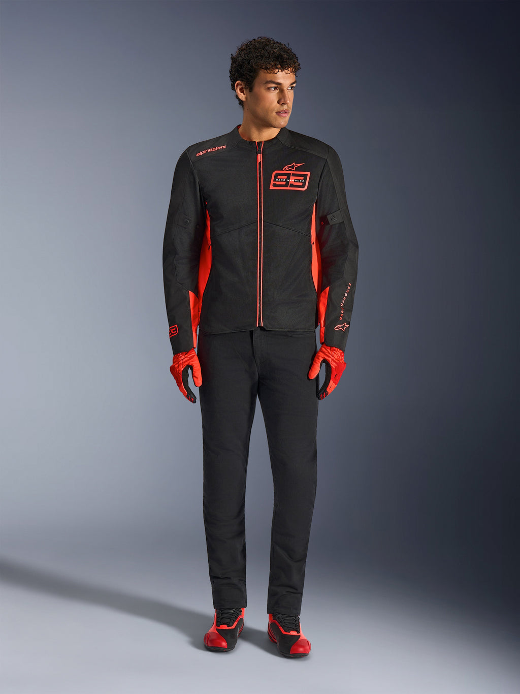 Alpinestars MM93 C-1 Air-jakke, motorcykeljakke, sort og rød fluo, med Marc Marquez-branding og 93-logo, båret af model med matchende røde handsker og sorte bukser, let tekstil- og mesh-konstruktion til bykørsel