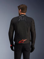 Alpinestars SMX Air-jakke, set bagfra, sort med lysende rødt Alpinestars-logo på lænden, tech-mesh-panel med høj luftgennemstrømning, Tech-Air Ready-branding, båret af en mandlig kører med sorte bukser og handsker