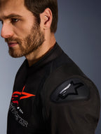 Alpinestars SMX Air jakke, sort og rød, nærbillede af DFS Lite skulderbeskytter med stjernelogo, båret af en mand med skæg, tekstil racing- og sportsmotorcykeljakke