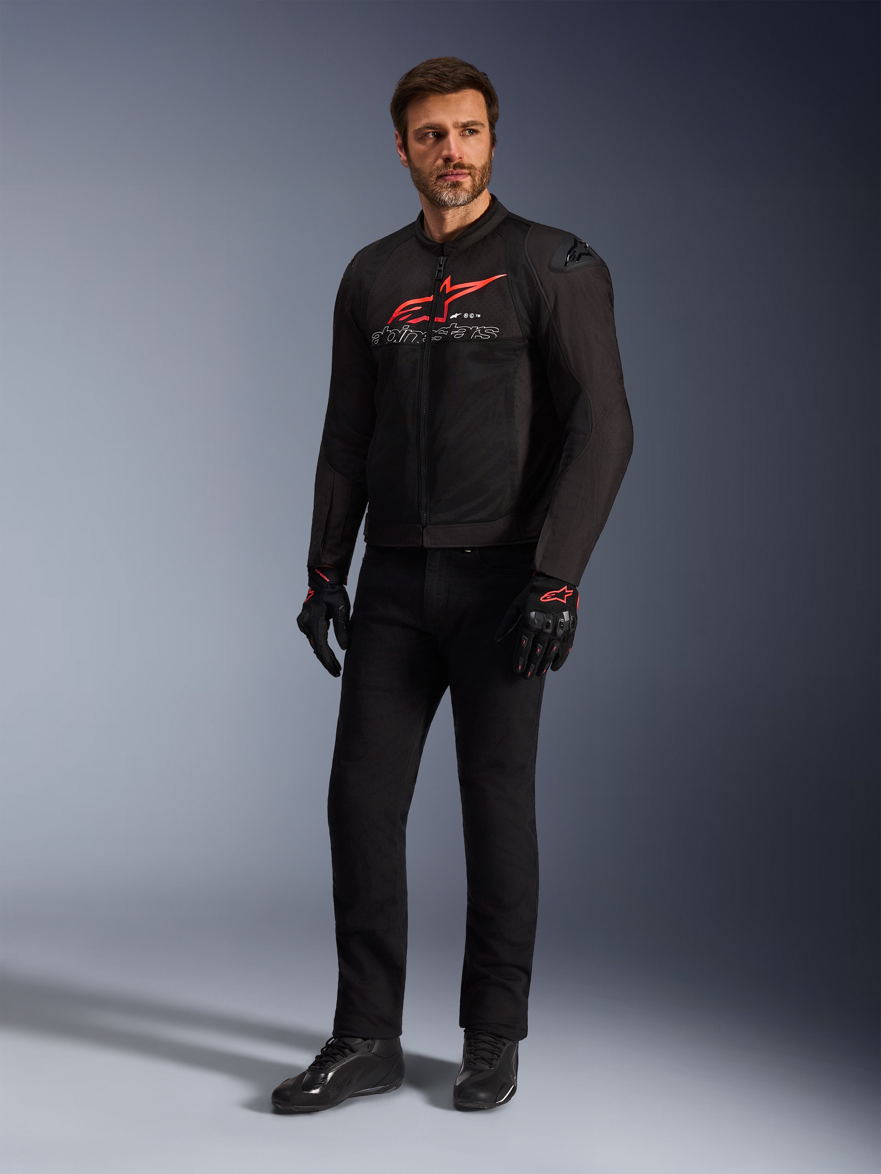 Mandlig model iført Alpinestars SMX Air-jakke i Black Bright Red White, kombineret med sorte tekniske bukser, sort-røde handsker og sorte køresko, med et markant rødt brystlogo og hvid branding, helkropsstudiebillede af sportsmotorcykeludstyr