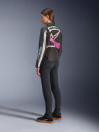 Alpinestars Idles Women’s Jacket, Motorcycle Jacket, Black Off White and Purple, viewed from the back on model, featuring a large wrap-around Alpinestars logo and vintage racing-inspired design, paired with dark jeans and black shoes.
