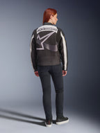 Alpinestars Idles damejakke, urban motorcykeljakke, sort og råhvid, set bagfra med et stort gråt Alpinestars-logo og ordmærke, båret med slim-fit sorte jeans og sneakers, vintage-inspireret design til bykørsel