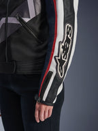 Alpinestars Idles damejakke, urban motorcykeljakke, Off White Flame Red Black, nærbillede af ærmet med et stort broderet Alpinestars-logo, røde og hvide racingstriber, sort tekstil- og læderkonstruktion og metallynlås-detaljer
