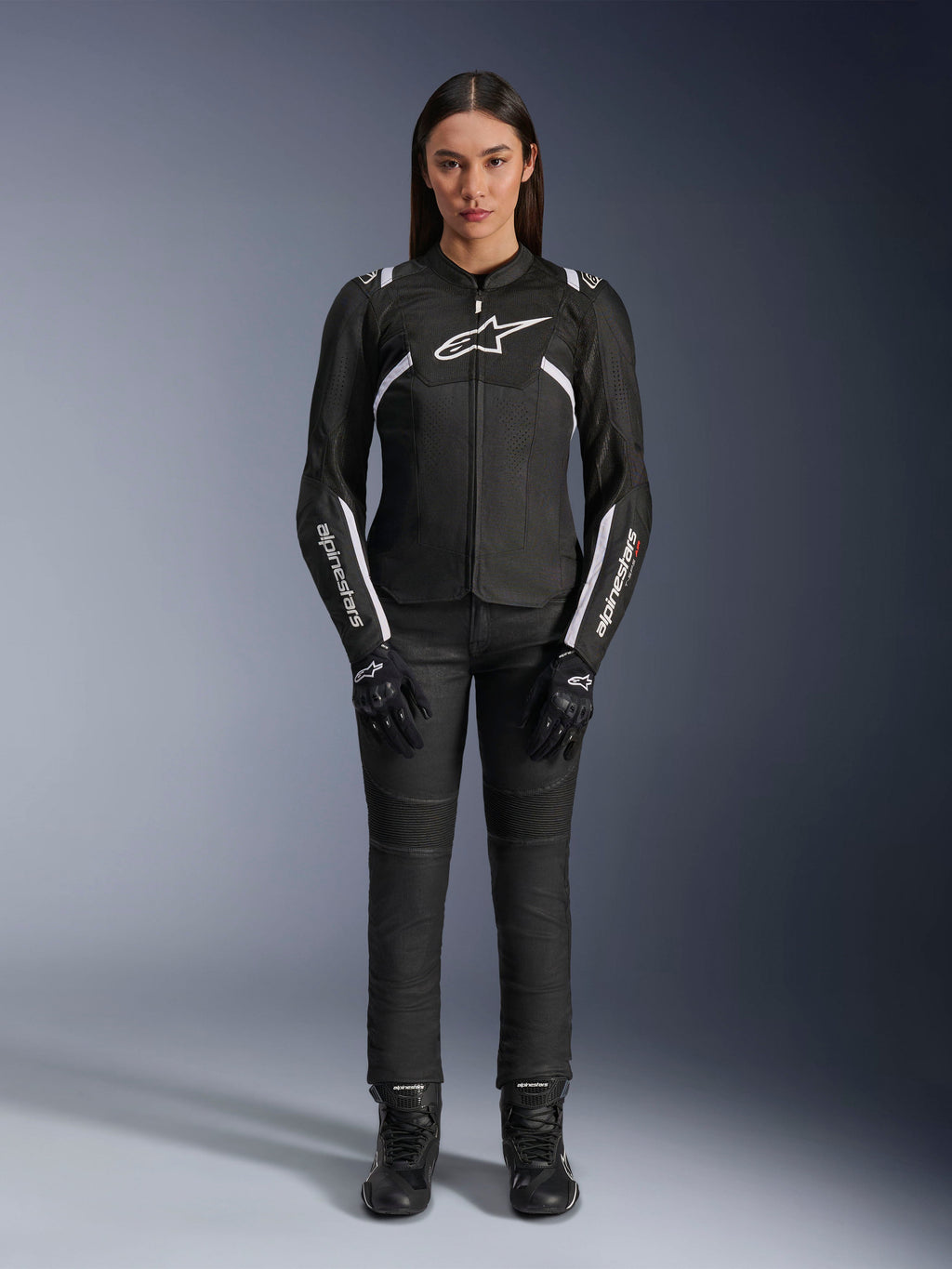 Alpinestars Stella T-Sps Air V2-jakke, motorcykeljakke til kvinder, sort og hvid, med mesh-paneler og hvide detaljer, båret med sorte bukser, handsker og støvler, atletisk pasform til bykørsel