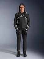 Alpinestars Stella T-Sps Air V2-jakke, motorcykeljakke til kvinder, sort og hvid, med mesh-paneler og hvide detaljer, båret med sorte bukser, handsker og støvler, atletisk pasform til bykørsel