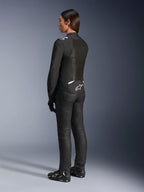 Alpinestars Stella T-Sps Air V2 jakke, sort og hvid, set bagfra med mesh-paneler og logo på den nederste del af ryggen, kombineret med sorte kørebukser og motorcykelsko, sportsligt tekstiludstyr til kvinder