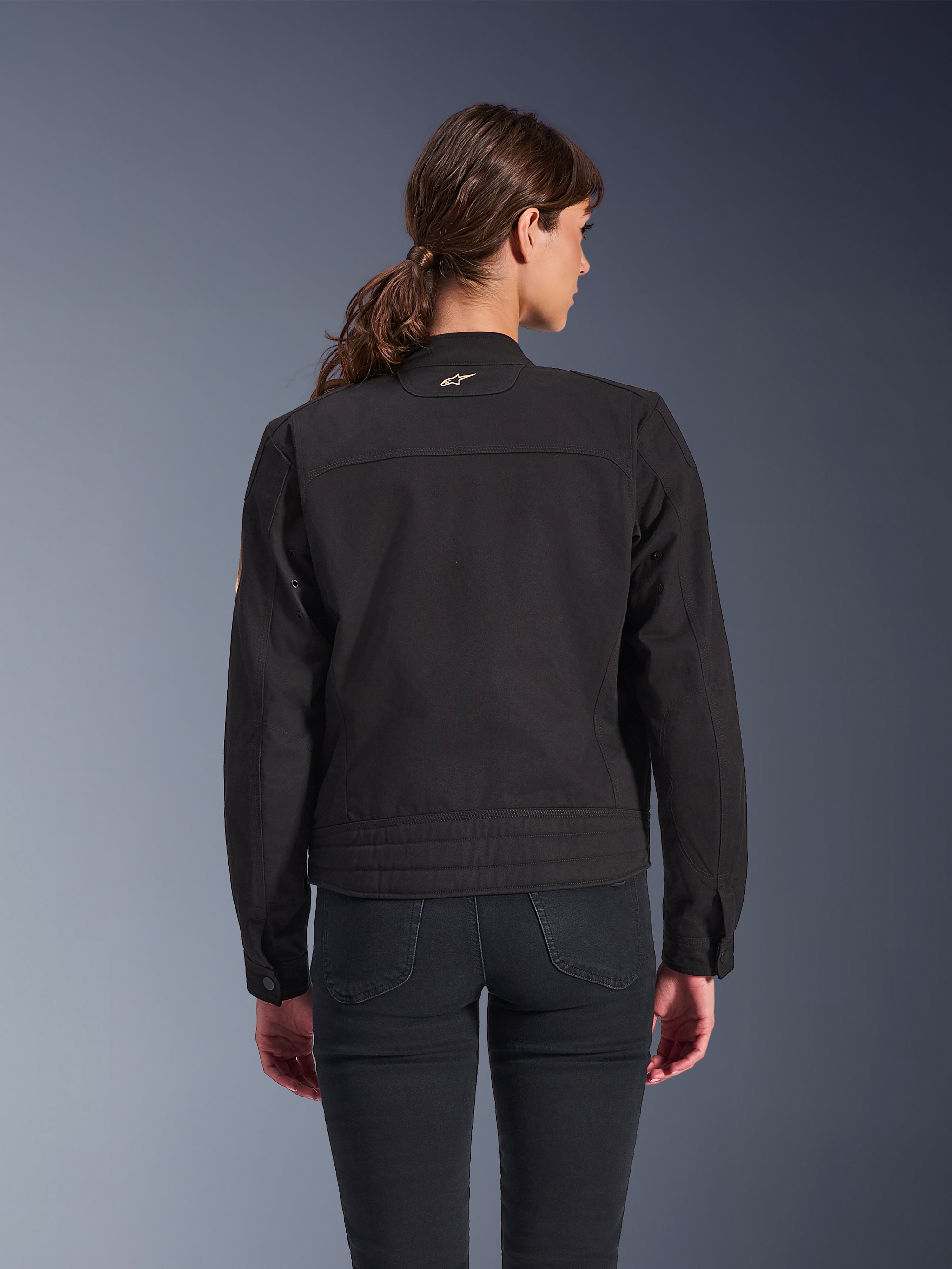 Alpinestars Stella Grace jakke til kvinder, sort, set bagfra, urban motorcykeljakke med klassisk arbejdstøjs-æstetik, tekstil polycotton twill-konstruktion, kombineret med sorte jeans