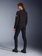 Alpinestars Stella Grace-jakke i sort, model set bagfra, der fremhæver vintage Oscar-spiralmærket på armen og det lille stjernelogo på kraven, kombineret med sorte motorcykelbukser og støvler til bykørsel