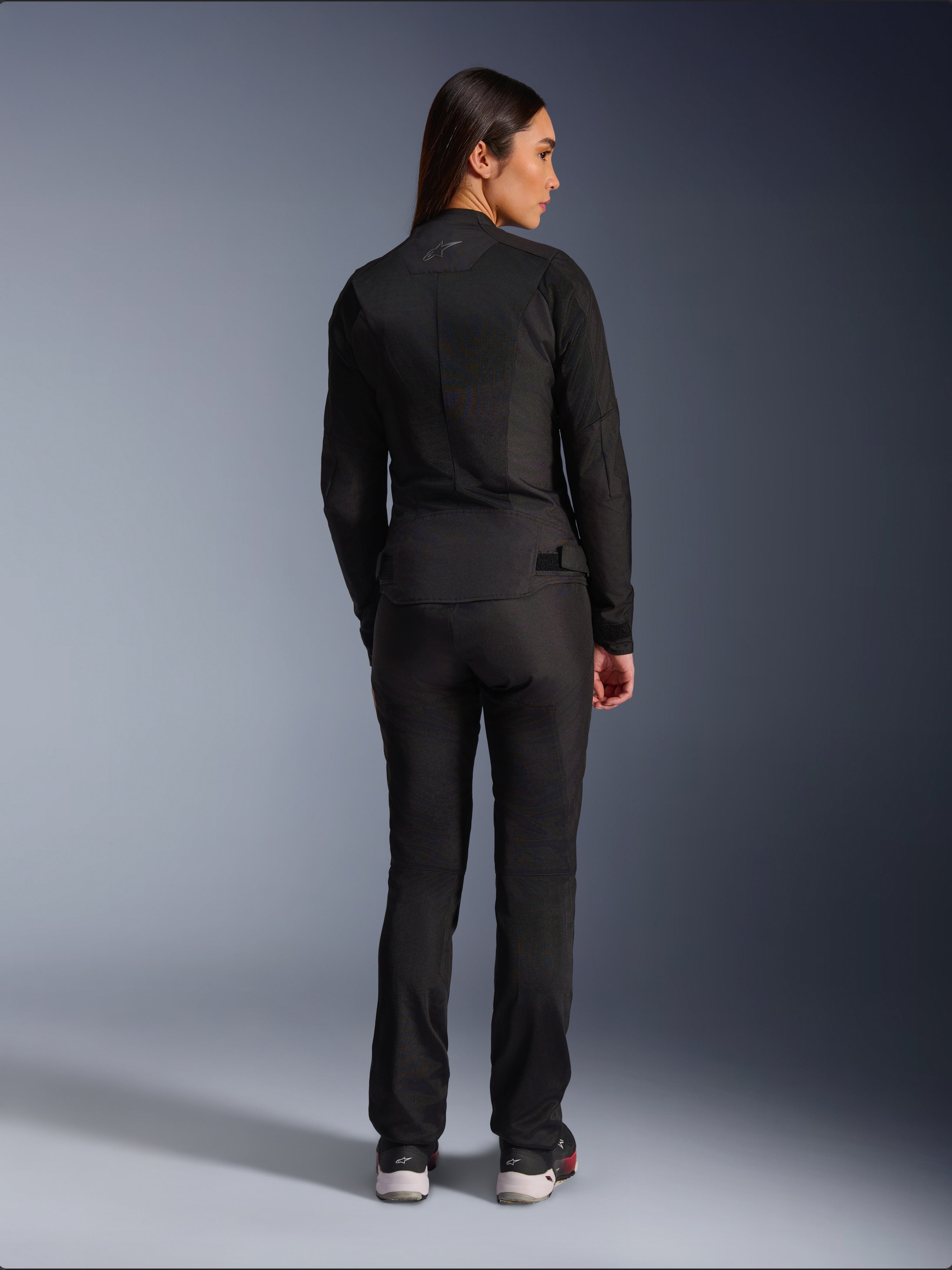 Alpinestars Stella C-1 Air jakke, tekstilmotorcykeljakke til damer, sort, set bagfra med mesh-konstruktion og diskret logo øverst på ryggen, båret med matchende sorte mc-bukser, moderne urban stil