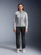 Kvinde iført Alpinestars Stella C-1 Air-jakke i sølv, set forfra, urban motorcykel tekstiljakke med tech mesh-paneler, stylet med sorte bukser og hvide sneakers, moderne køreudstyr