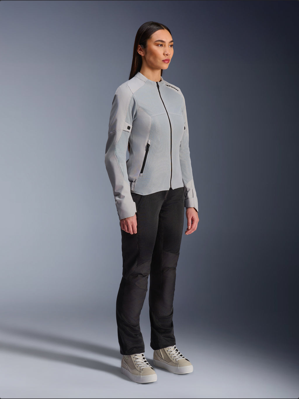 Kvinde iført Alpinestars Stella C-1 Air Jacket i Silver, letvægts tekstil- og mesh-motorcykeljakke, stylet med sorte motorcykelbukser og afslappede sneakers, ren urban køreæstetik