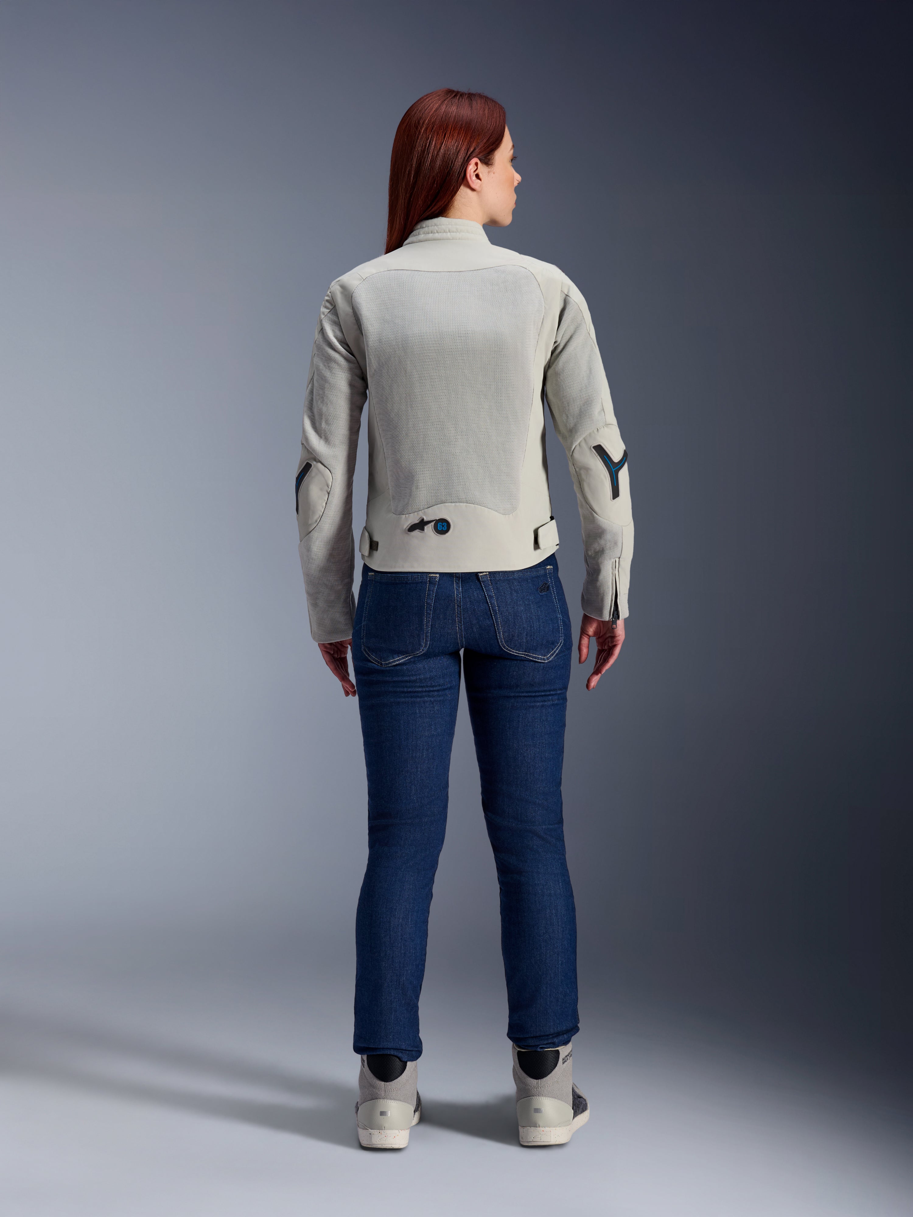 Alpinestars Stella Circal-1 Air Jakke til kvinder i Metal Gray og Methyl Blue, set bagfra, med store mesh-ventilationspaneler på ryggen og armene, båret med mørkeblå denimjeans og grå motorcykelsko for et moderne urbant motorcykel-look.