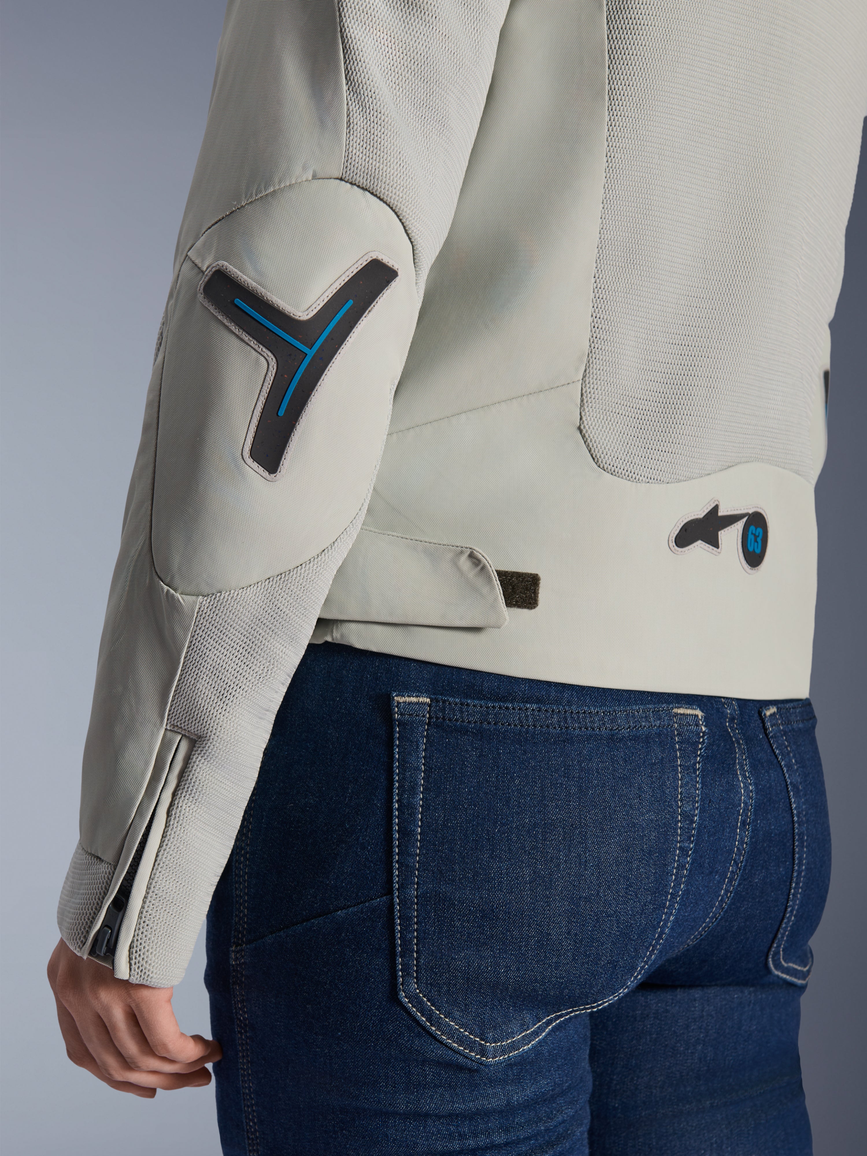 Alpinestars Stella Circal-1 Air damejakke i Metal Gray og Methyl Blue, tætbillede af ryg- og ærmedetaljer med mesh-paneler, neonblå detaljer på albue og talje, justerbar strop, båret med mørkeblå denimjeans