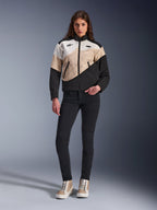 Alpinestars Stella Moshell-jakke til kvinder, urban motorcykeljakke med et asymmetrisk farveblokeret design i sort, sand og off-white, båret med sorte slim-fit bukser og sandfarvede high-top sneakers, moderne streetwear-æstetik til kørere