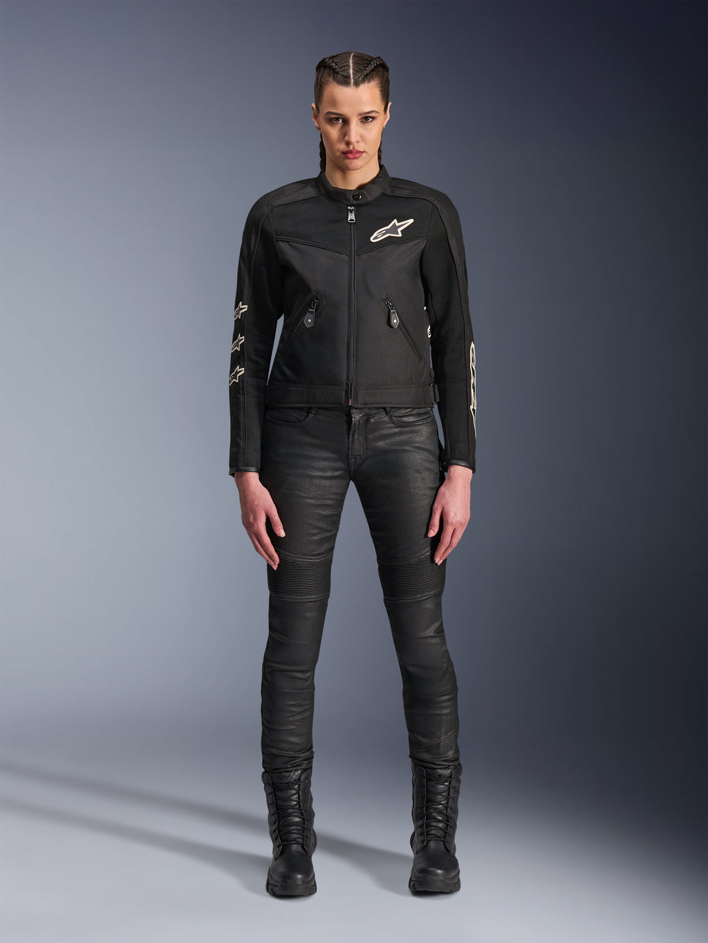 Kvindelig model iført Alpinestars Stella T-Dyno Air-jakke, motorcykeljakke til kvinder i sort, med 3D-mesh-paneler og hvide Astars-logoer, kombineret med sorte slim-fit kørebukser og sorte snørestøvler, urban kørestil.