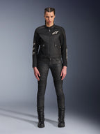 Kvindelig model iført Alpinestars Stella T-Dyno Air-jakke, motorcykeljakke til kvinder i sort, med 3D-mesh-paneler og hvide Astars-logoer, kombineret med sorte slim-fit kørebukser og sorte snørestøvler, urban kørestil.