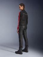 Woman wearing Alpinestars Stella T-Dyno Air Jacket in Black Bright Red Fuchsia, paired with black riding pants and black boots, side-profile view highlighting the red and fuchsia sleeve graphics and tailored biker fit.