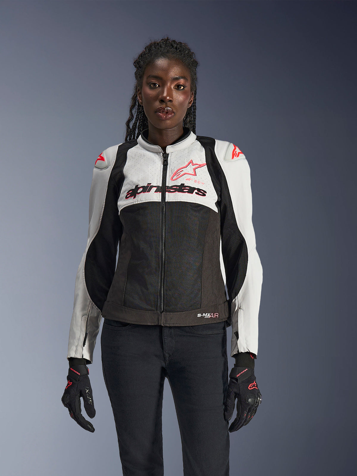Alpinestars Stella SMX Air jakke til kvinder, Ice Gray, sort og Coral Fluo, med mesh-konstruktion og perforerede paneler, båret af en kvindelig model med sorte motorcykelhandsker og bukser, set forfra