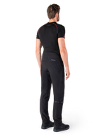 Alpinestars Alden bukser, sorte, urbane motorcykelbukser vist bagfra på en model, båret med et sort kortærmet baselayer og sorte køresko, med quiltede detaljer og reflekterende MO.ST.EQ.-branding på bagstykket.