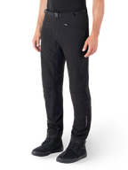 Alpinestars Alden bukser, urbane motorcykelbukser, sort, teknisk softshell-materiale med regular fit, med magnetisk taljespænde, quiltede sidepaneler, lynlåslommer og subtil branding på underbenet, vist med sorte køresko