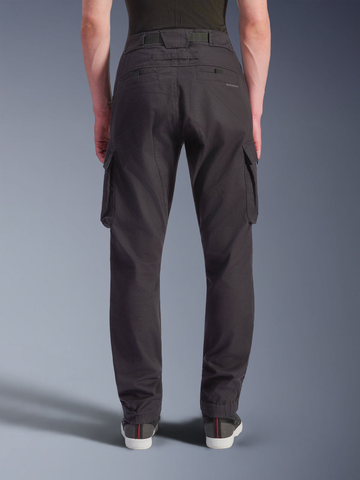 Alpinestars Flex-AST Cargo Bukser - Short, urbane motorcykelbukser, sort, set bagfra med en regular tilspidset pasform og elastiske sømme, store cargolommer i siden og diskret branding på baglommen, båret med casual sneakers