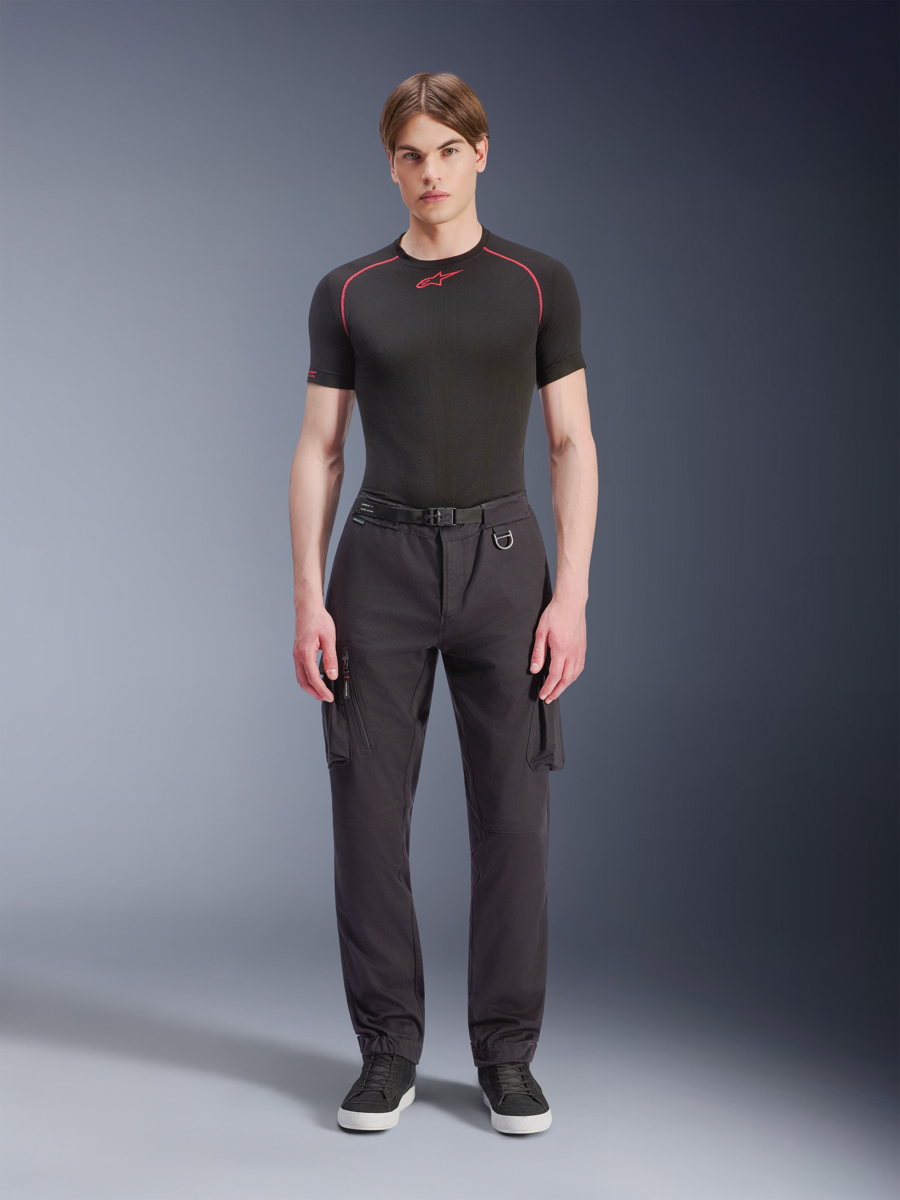 Alpinestars Flex-AST Cargo Pants - Short, sorte, båret af en mandlig model med en sort performance t-shirt og sorte sneakers, urbane motorcykelbukser med flere cargolommer, tilspidset pasform, indbygget bælte med spænde og D-ring