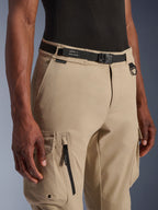Alpinestars Flex-AST Cargo bukser - Short, lys beige, nærbillede af talje og lår, med sort justerbart bælte med Alpinestars-branding, metal D-ring og funktionelle cargolommer med lynlåse og klapper med trykknapper, urbant moderne motorcykeludstyr