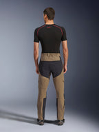 Alpinestars Flex-AST Explorer bukser, Walnut Black, set bagfra på model, med forstærket sort sæde og brunt stræktekstil, kombineret med sort baselayer og tekniske motorcykelstøvler, slidstærkt adventure-køreudstyr