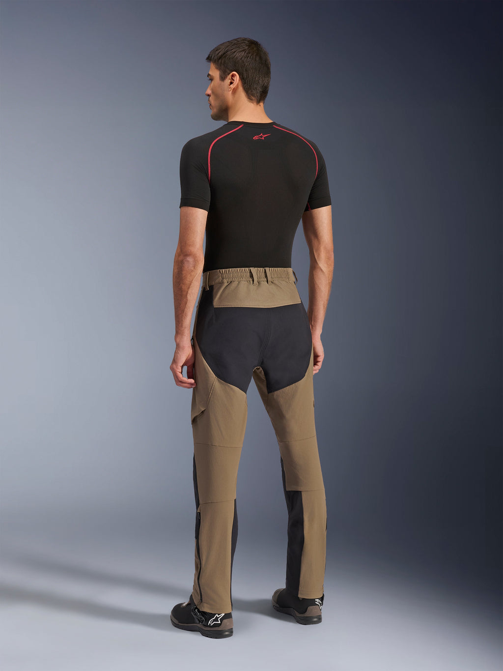 Alpinestars Flex-AST Explorer bukser, adventure-motorcykelbukser, Walnut Black, set bagfra på model, sorte ripstop-paneler på sæde og ben, strækbar tekstilkonstruktion, lange lynlåse på underbenene til adventure touring
