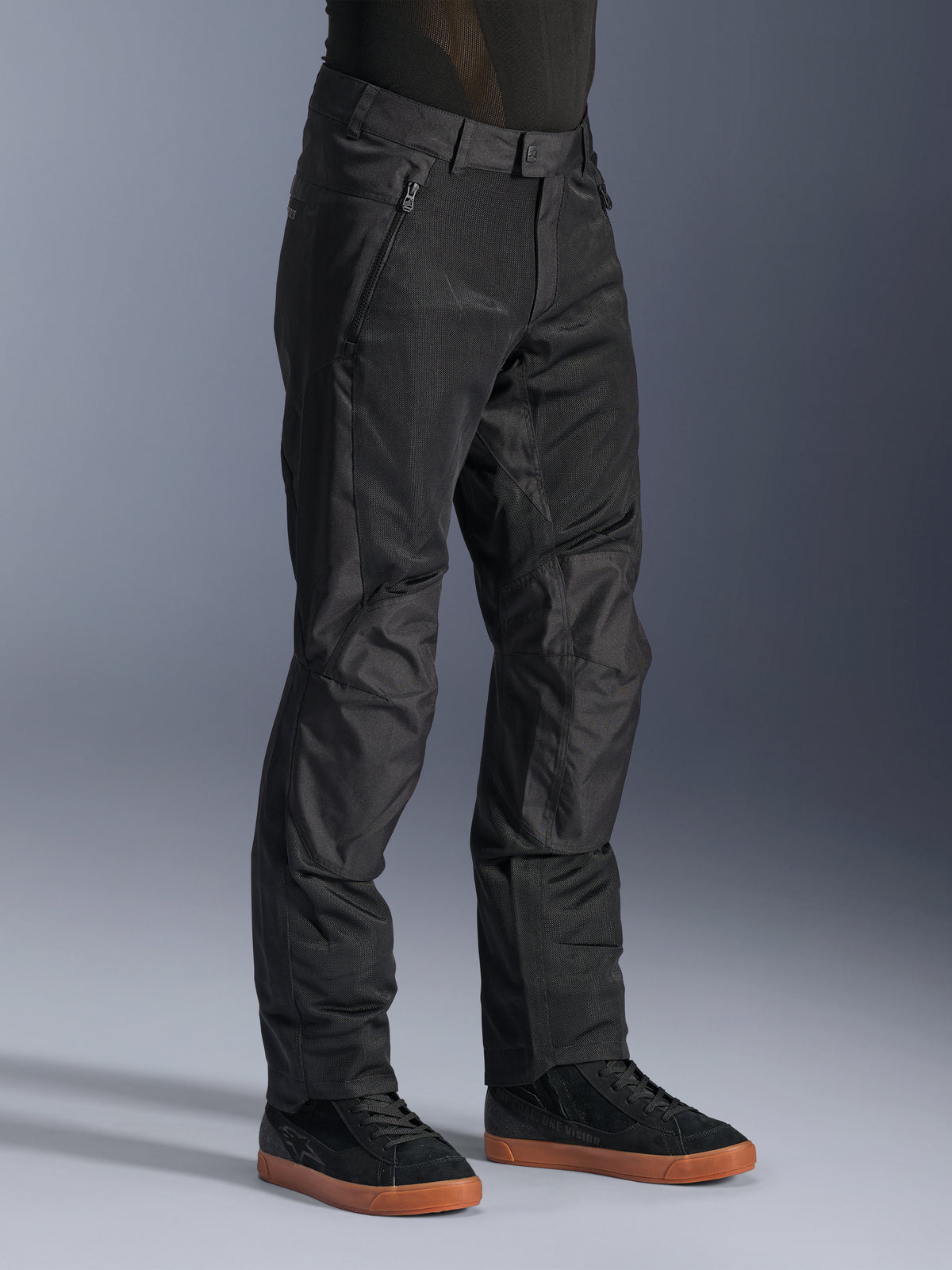 Alpinestars C-1 Air bukser, urbane motorcykelbukser, sort, med åndbare tech-mesh-paneler og polyfabric-konstruktion, båret med sorte sneakers, rent og funktionelt design til bykørsel.