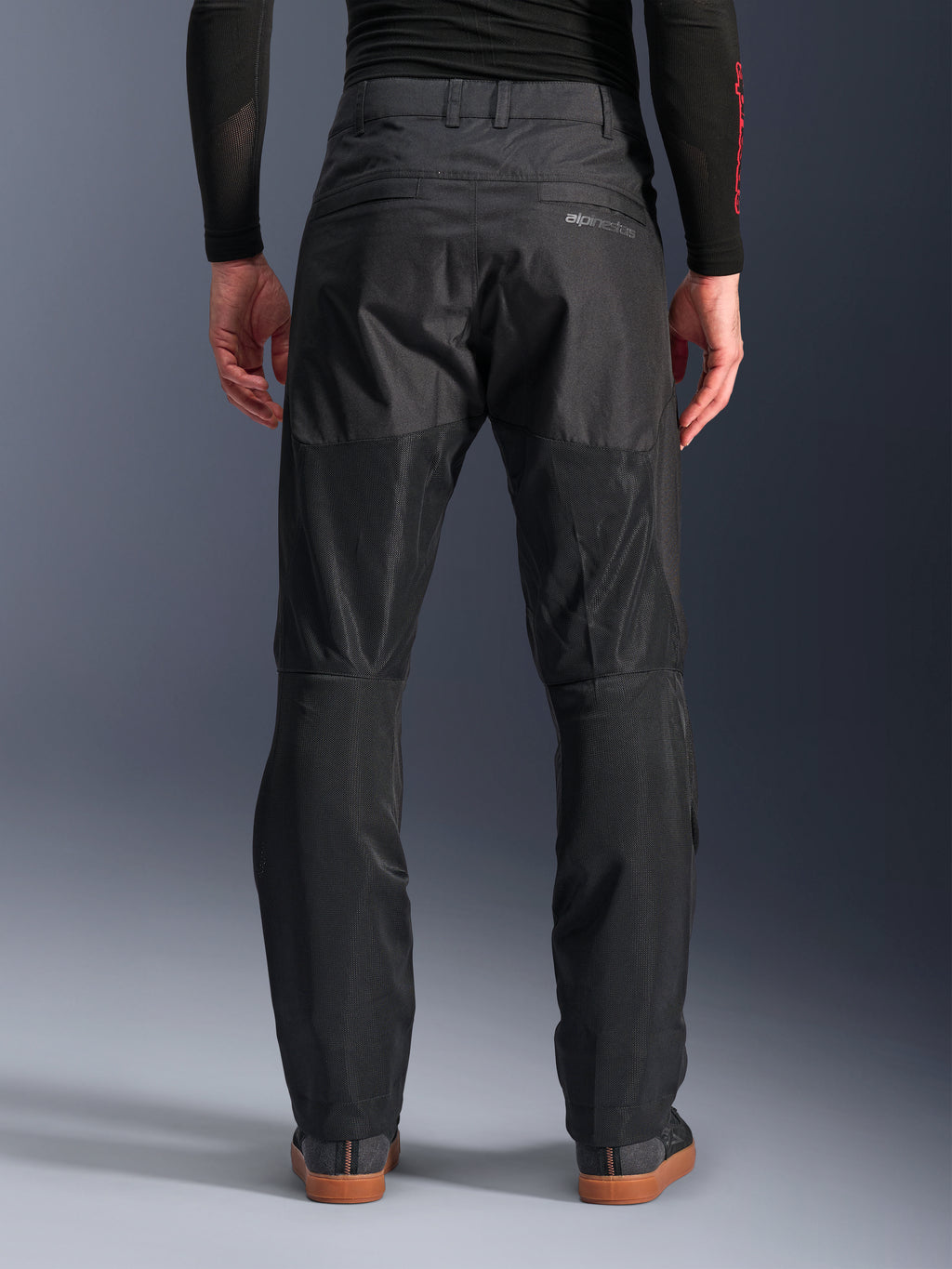 Alpinestars C-1 Air bukser, set bagfra, sort, urban tekstil-motorcykelbukser med store tech mesh-paneler bag på benene til ventilation, rent design med diskret branding, vist med et sort baselayer og afslappede køresko