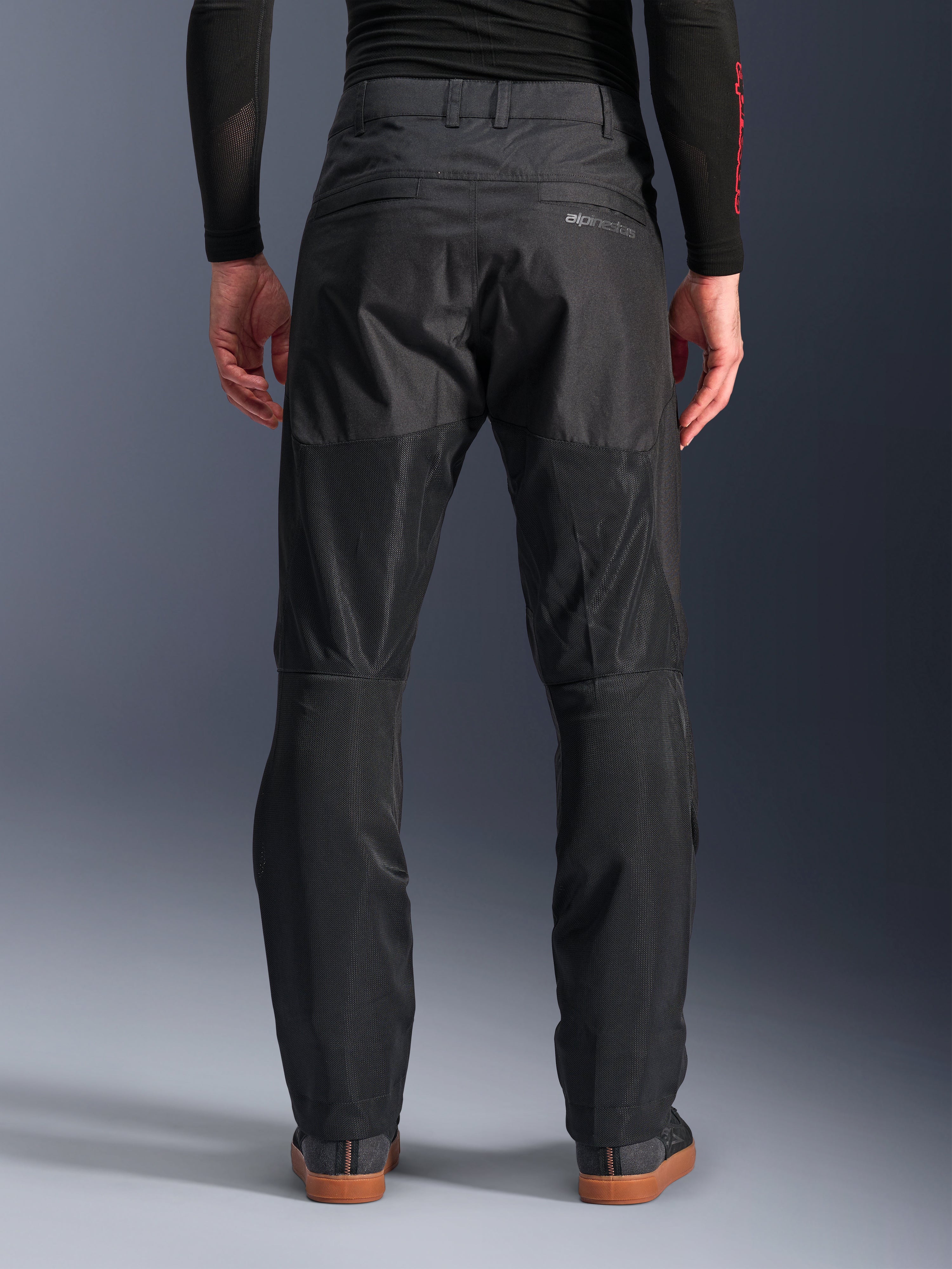 Alpinestars C-1 Air bukser, set bagfra, sort, urban tekstil-motorcykelbukser med store tech mesh-paneler bag på benene til ventilation, rent design med diskret branding, vist med et sort baselayer og afslappede køresko