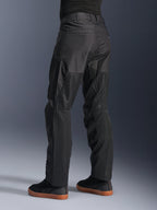 Alpinestars C-1 Air bukser, urbane motorcykelbukser, sorte, set bagfra med store tech mesh-paneler på bagsiden af benene til ventilation, stilrent design til bykørsel, båret med afslappede sorte sneakers.