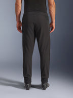 Alpinestars Aeroshell Airflow bukser, sort, set bagfra, med laserperforerede zoner på læggene og mesh-paneler, båret med sorte Alpinestars-støvler, letvægts softshell-design til sport og touring