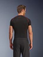 Alpinestars Aeroshell Airflow bukser, set bagfra, sorte, letvægts softshell-konstruktion med integrerede mesh-sidepaneler, kombineret med et sort basislag med røde kontrastsyninger, sportsligt motorcykeludstyr