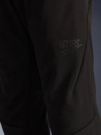 Alpinestars Aeroshell Airflow bukser, sorte motorcykelbukser, nærbillede af lårområdet med et ophøjet sort ASTARS-logo, letvægts stræk-softshell-materiale med ergonomisk sømdesign