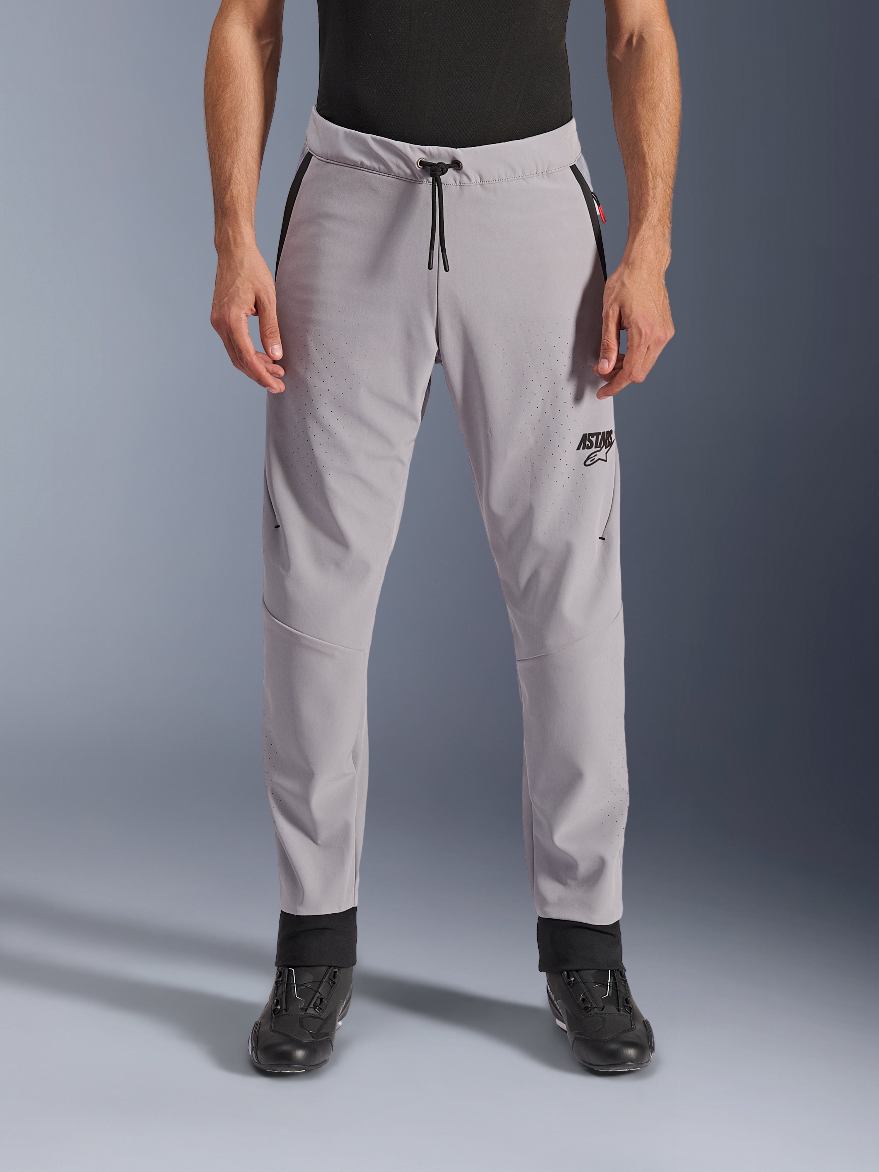 Alpinestars Aeroshell Airflow bukser, mellemgrå, set forfra med laserperforerede zoner på lår og skinneben, sort snoretræk i taljen og sort ASTARS-logo, letvægts softshell-chassis til kørsel i varmt vejr