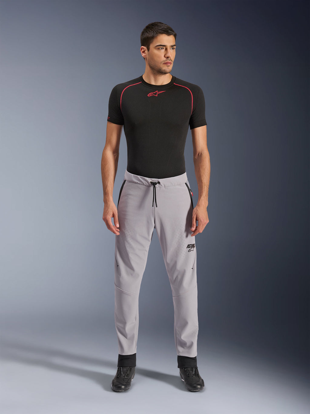 Alpinestars Aeroshell Airflow bukser, Mid Gray, lette tekstilbukser med laserperforerede ventilationszoner og snøre i taljen, båret af en model med sort kompressionsshirt og sorte motorcykelstøvler, rent og moderne sportskørselsdesign