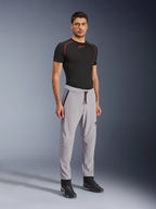 Alpinestars Aeroshell Airflow bukser, motorcykelbukser, Mid Gray, båret af en model med en sort teknisk t-shirt og sorte motorcykelsko, med laserperforerede ventilationszoner, elastisk linning med snoretræk og en strømlinet sportspasform.