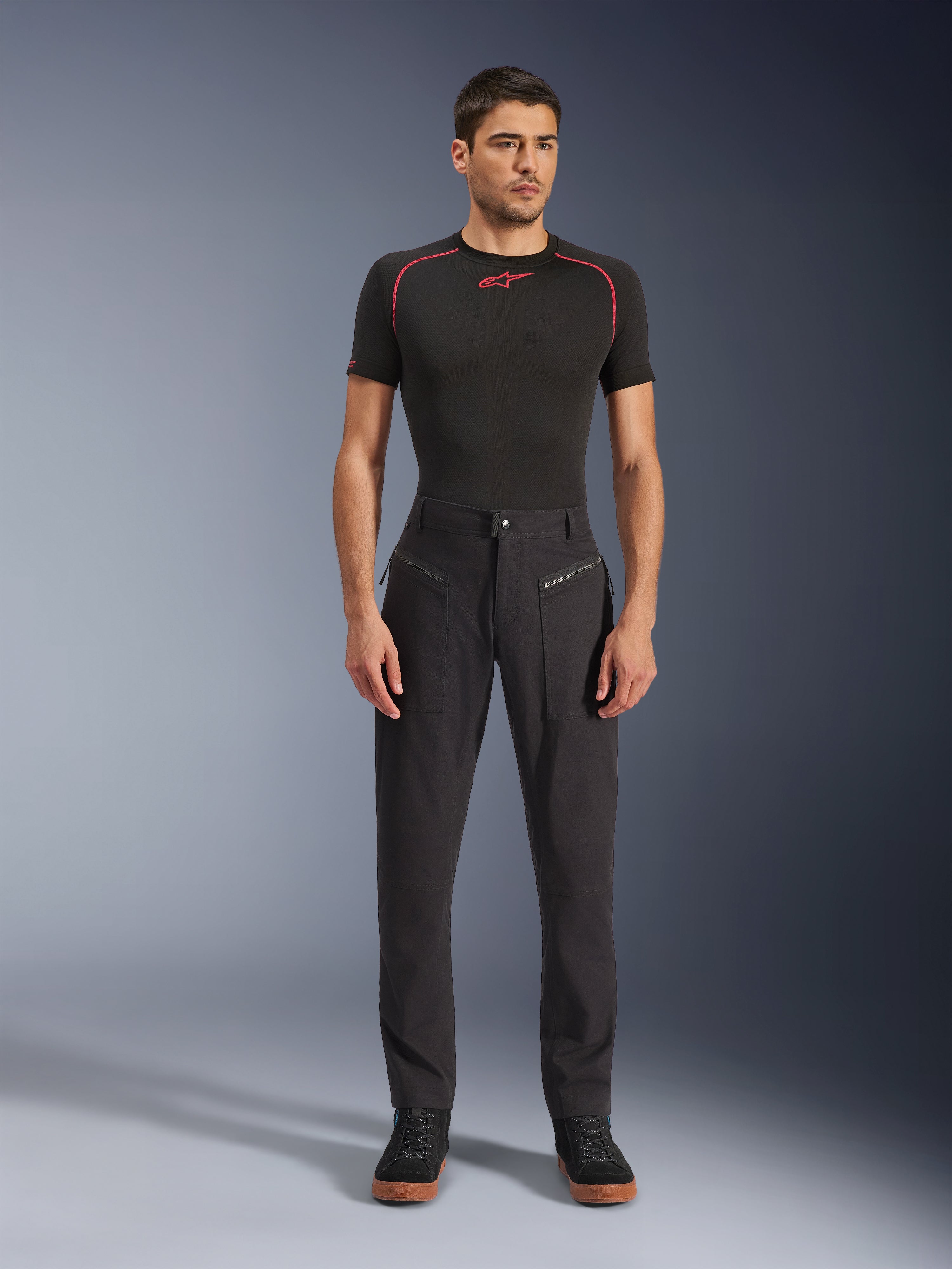 Alpinestars Flex-AST Canvas Pants, Urban Motorcycle Pants, Black, worn by a model with a black short-sleeved base layer featuring red stitching and black casual sneakers, highlighting the front zippered pockets and ergonomic canvas design.