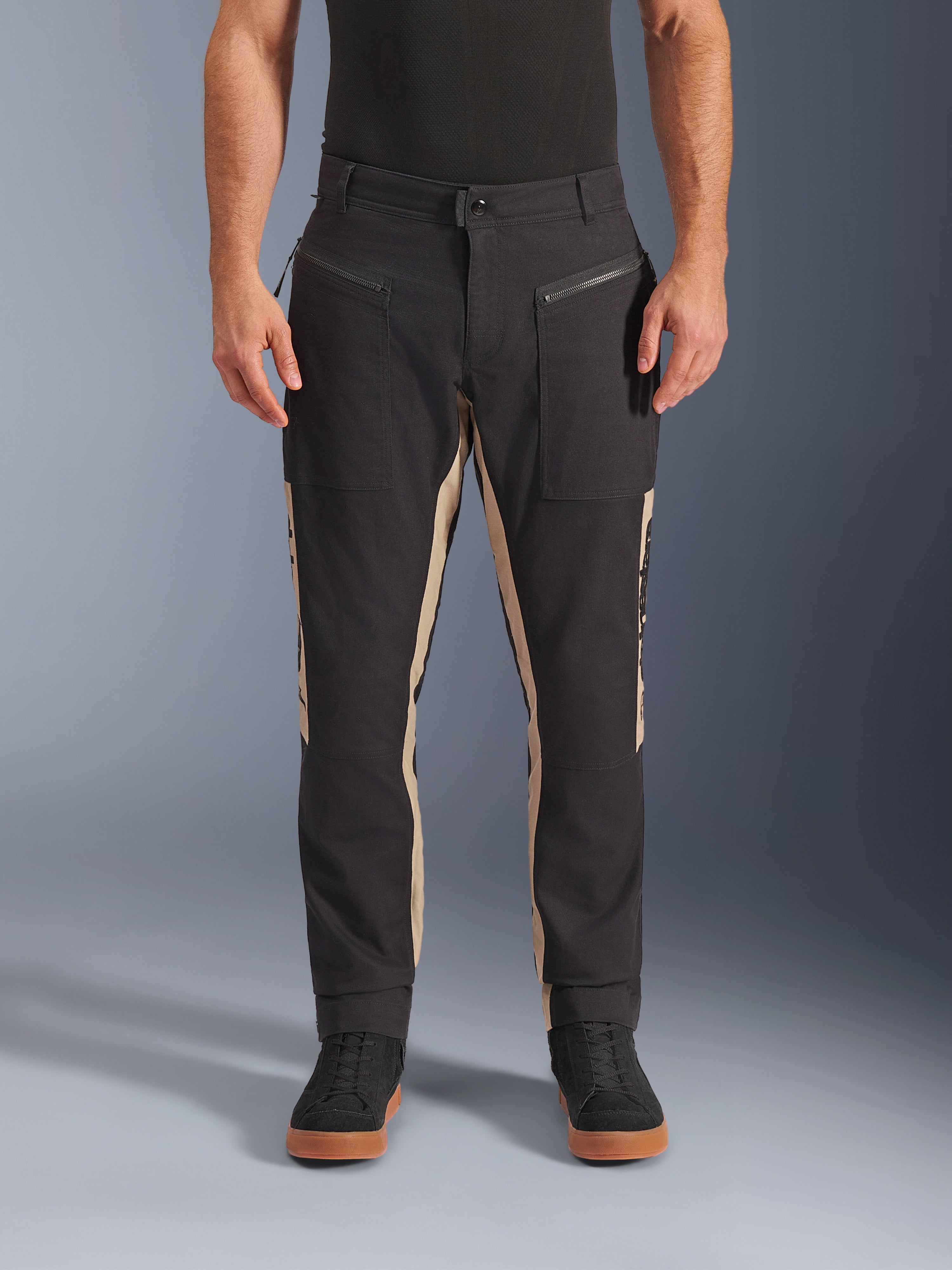 Alpinestars Flex-AST Canvas bukser, urbane motorcykelbukser, sort og aluminium, heritage-inspireret arbejdstøjsdesign, frontlommer med lynlås, ergonomisk motorcykelsnit, båret med afslappede sorte sneakers og sort t-shirt, utilitaristisk streetstyle