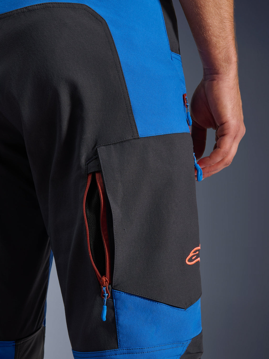 Alpinestars Maxdura Dual bukser, Royal Blue og Deep Gray, nærbillede af cargolomme med lynlås i siden, blå lynlåsstropper, orange broderet logo, adventure motorcykeludstyr