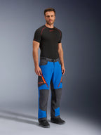 Alpinestars Maxdura Dual bukser, adventure motorcykelbukser, kongeblå og mørkegrå, med orange lynlåsdetaljer og logoer, båret af en model med sort baselayer og støvler, teknisk design med forstærkede paneler til dual-sport kørsel