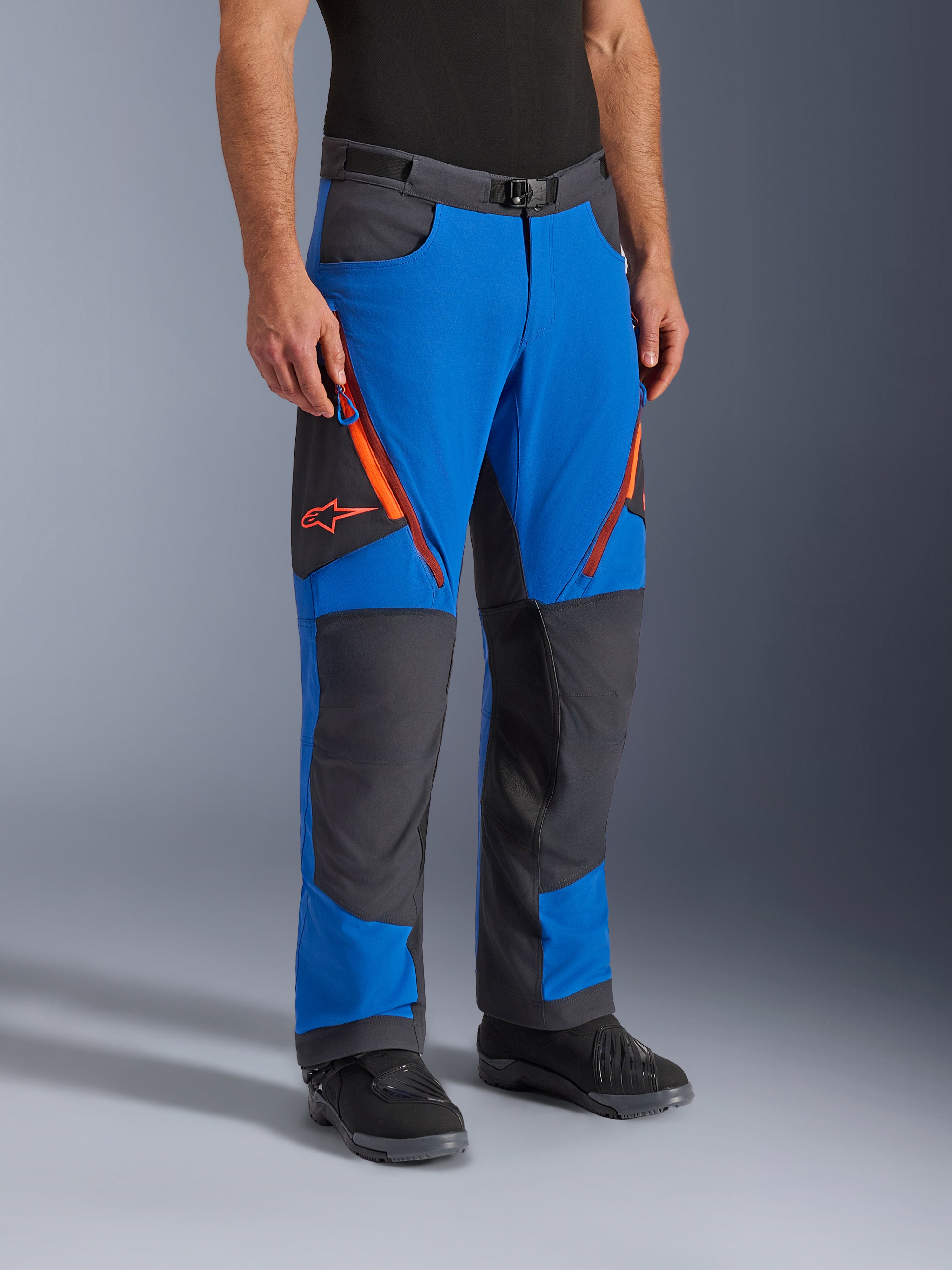 Alpinestars Maxdura Dual bukser, adventure motorcykelbukser, kongeblå og mørkegrå med orange detaljer, lynlåsventiler på lårene, forstærkede knæpaneler og bælte med magnetspænde, teknisk over-støvle-design til dual-sport kørsel.