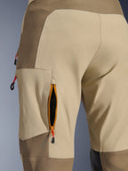 Alpinestars Maxdura Dual bukser i Walnut Aluminum, nærbillede af ventilationsåbning med lynlås på låret, orange kant og sort mesh, sandfarvet og brunt kraftigt stretch-polyamidstof, røde trækstropper